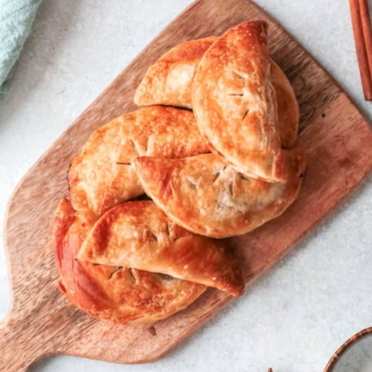 Golden-brown pumpkin hand pies cooked in the air fryer, showing a flaky crust and creamy spiced pumpkin filling inside.