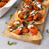 Air fryer roasted cherry tomatoes spooned over toasted bruschetta with fresh basil