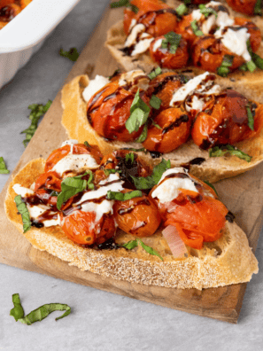 Air fryer roasted cherry tomatoes spooned over toasted bruschetta with fresh basil