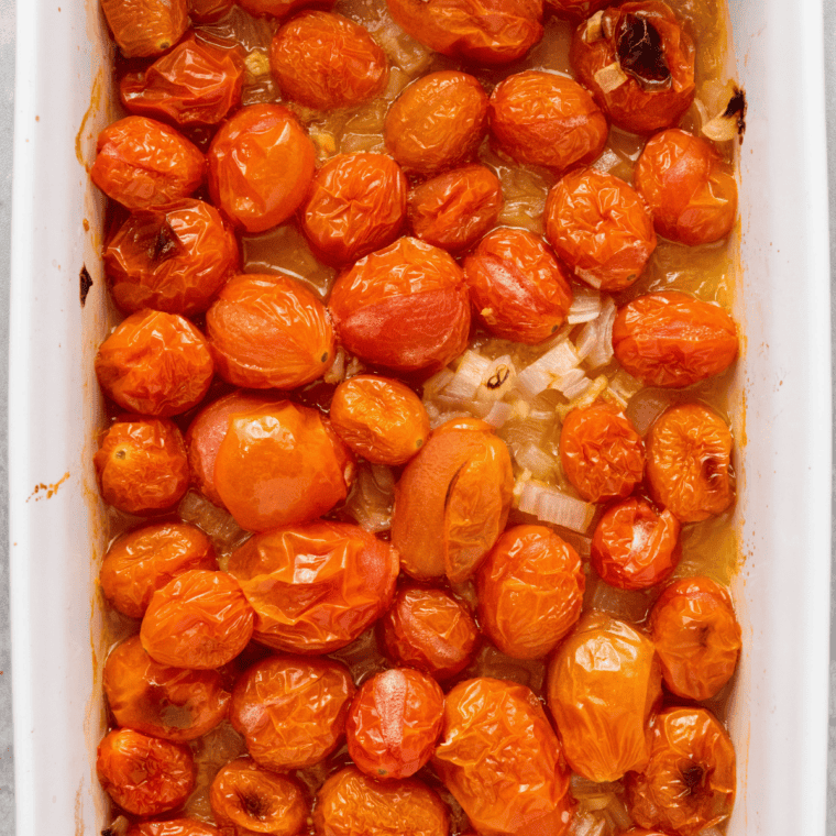 Cherry tomatoes in the air fryer basket after roasting, skins split and edges browned