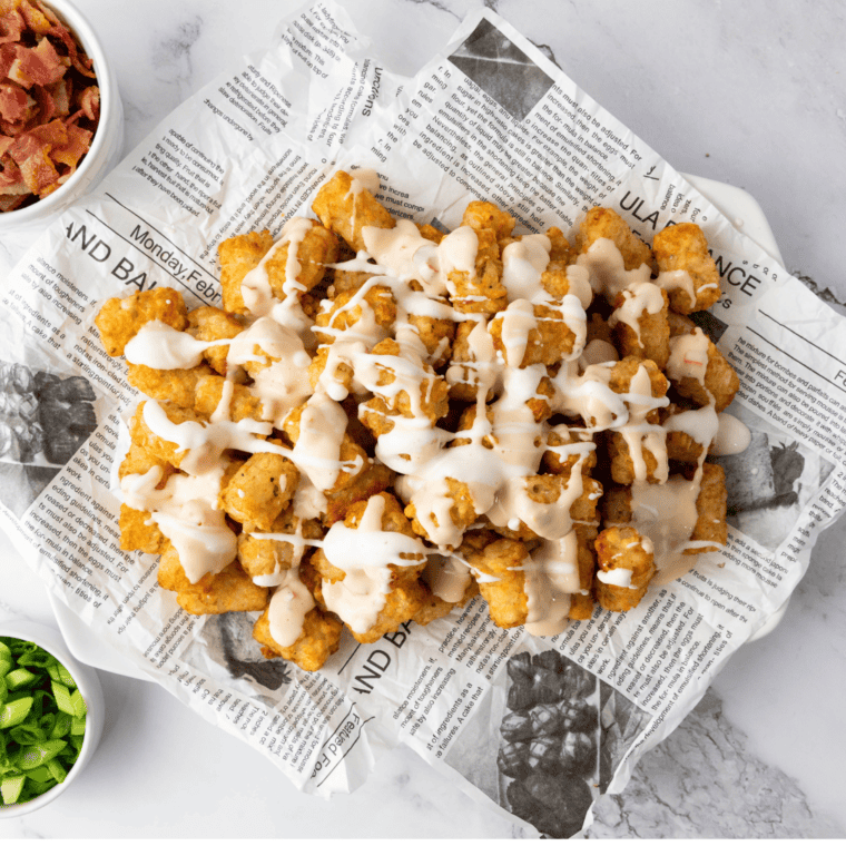 Cheddar bacon loaded tater tots on a tray, topped with melted cheese, crispy bacon, and garnished with green onions.