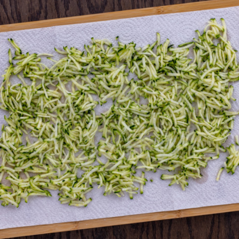 Grated zucchini and walnuts folded into zucchini bread batter with a spatula