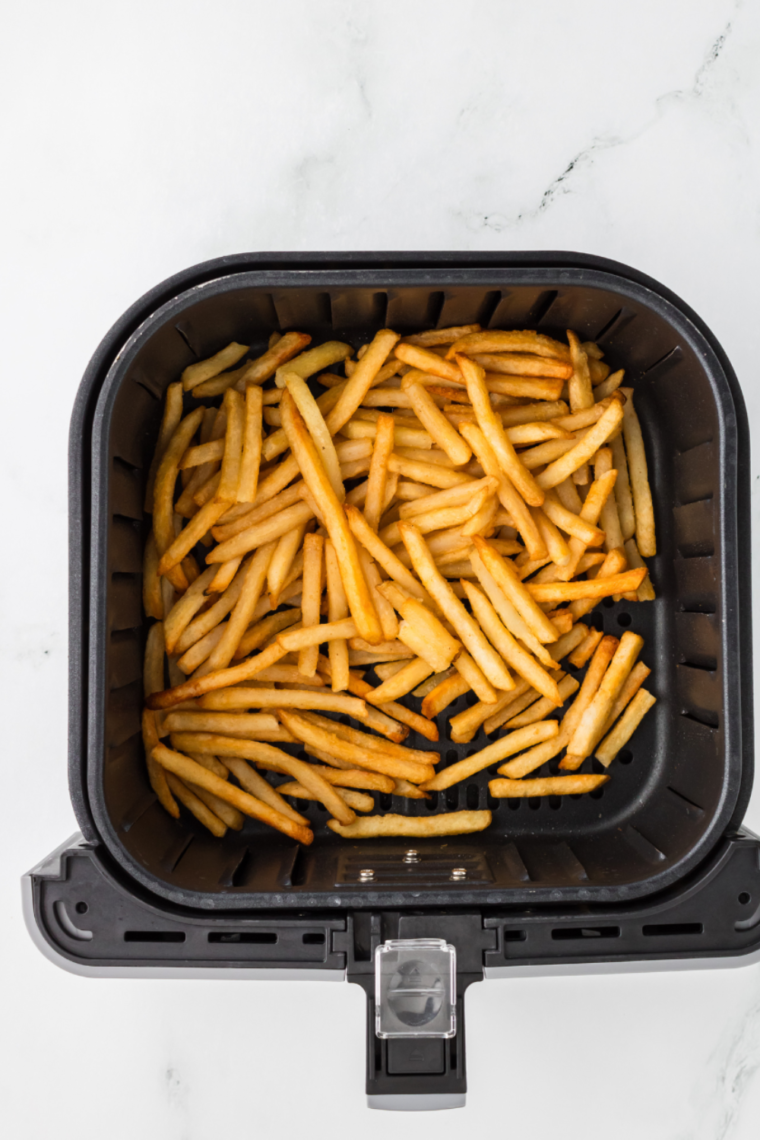 Cooked frozen French fries in the air fryer basket.
