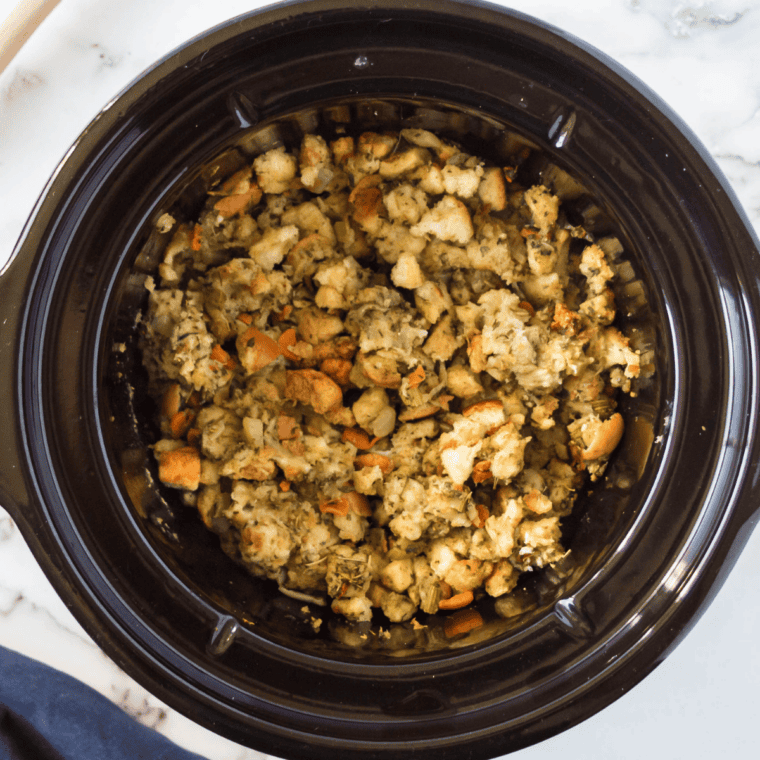 Crockpot stovetop stuffing fluffed with a fork in a black slow cooker