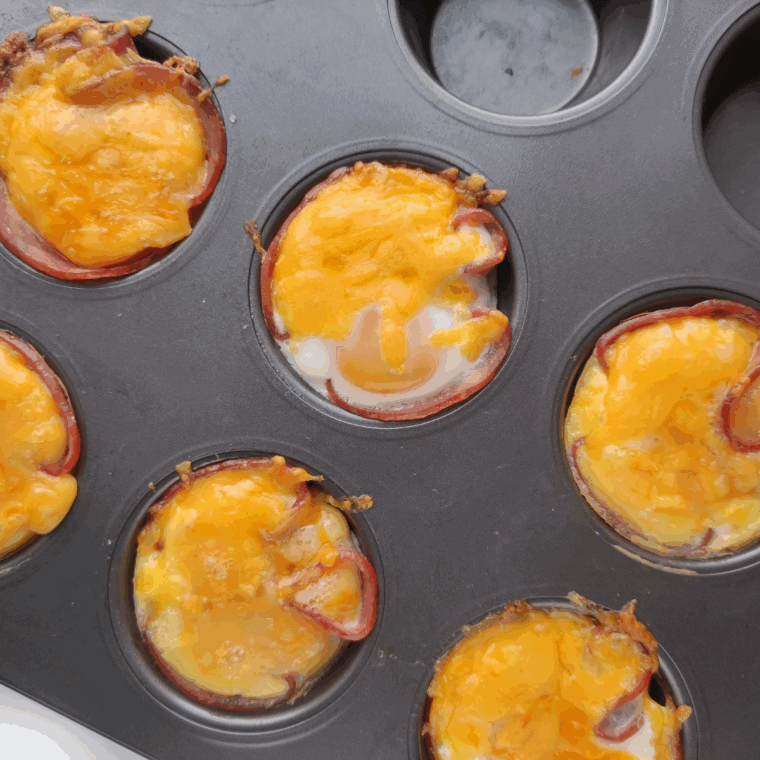 Close-up of a cooked egg cup showing a runny yolk and crispy ham edges.