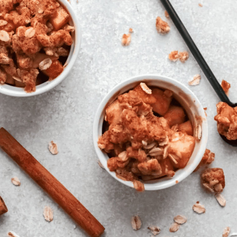 Air fryer apple crisp served with a drizzle of caramel sauce and a sprinkle of cinnamon, garnished with fresh apple slices.
