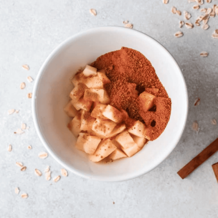 Sliced apples in a bowl, mixed with cinnamon and sugar, ready to be layered.