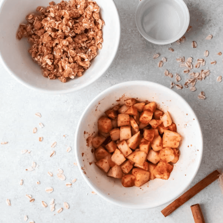 A bowl of oats, flour, brown sugar, and butter being mixed together to form the crisp topping.