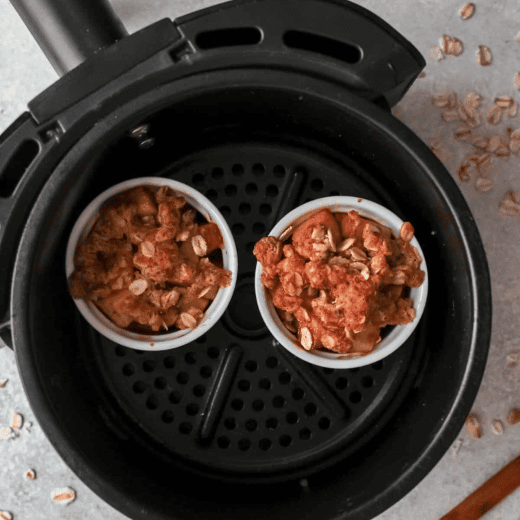 The baking dish filled with apple crisp positioned inside the air fryer basket, ready for cooking.


