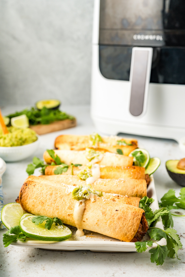 Crispy air fryer beef and bean taquitos filled with seasoned beef, refried beans, and melted cheese served with salsa and dipping sauce