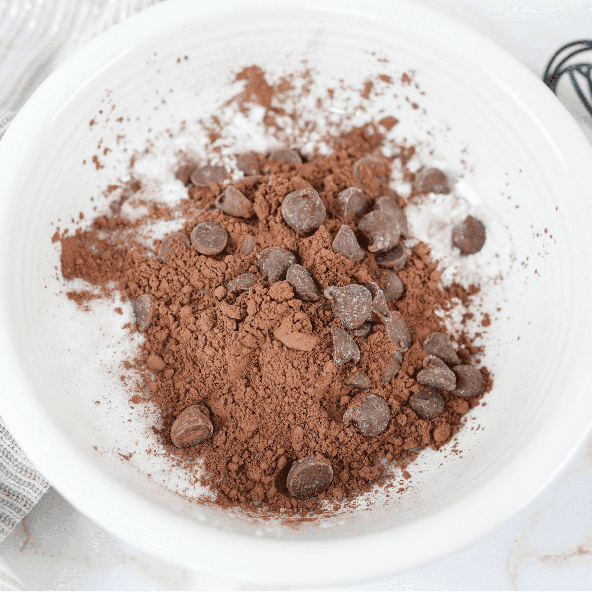 Dry brownie ingredients mixed in mug followed by wet ingredients stirred together to form smooth chocolate batter for air fryer mug brownie recipe