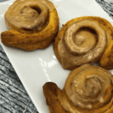 Pumpkin cinnamon rolls made in the air fryer with creamy glaze.