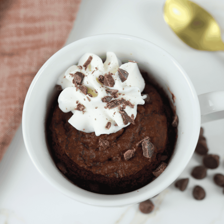 A warm, gooey chocolate mug cake cooked in an air fryer, topped with a dusting of powdered sugar.