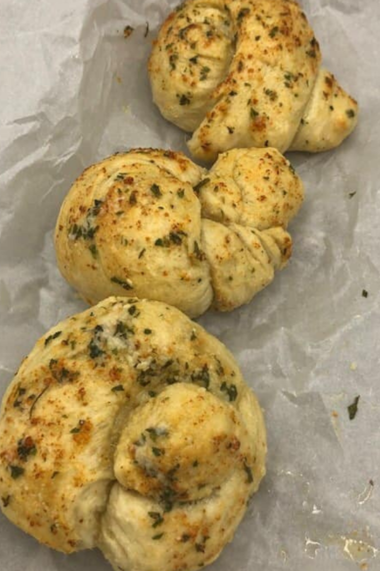 Golden air fryer garlic knots brushed with melted garlic butter and sprinkled with Parmesan and parsley.