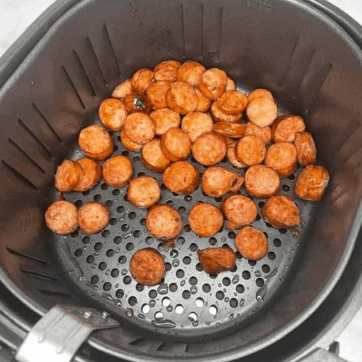 Sliced kielbasa sausage cooked to golden crisp in the air fryer basket.