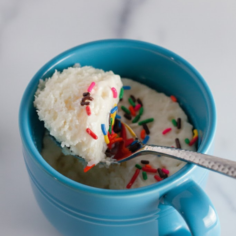 Mug cake topped with whipped cream ready to serve.