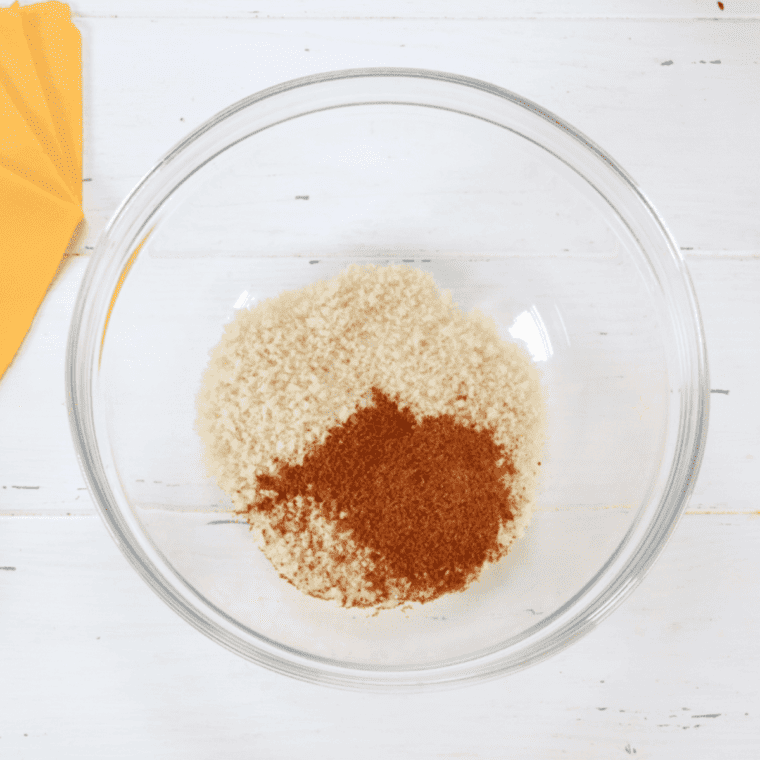 Adding panko breadcrumbs and Old Bay seasoning to a shallow dish, while beating an egg in another bowl.