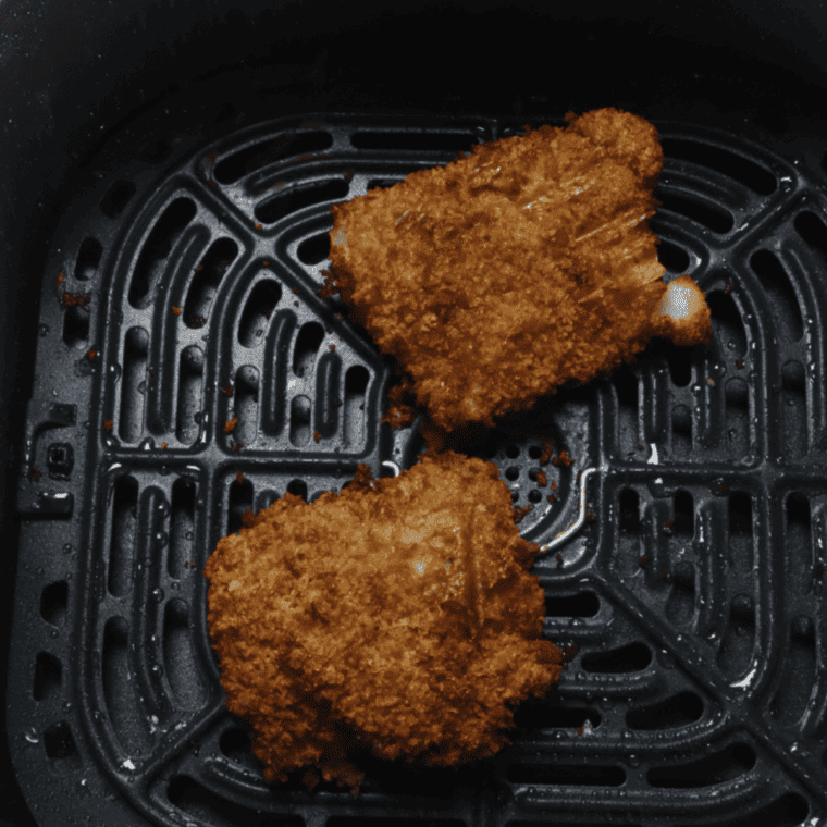 Cooked cod in the air fryer basket.