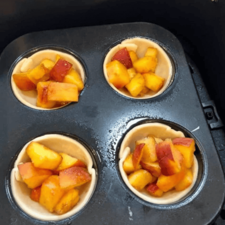 Golden air fryer muffin tin peach pies with juicy peach filling, ready to serve.