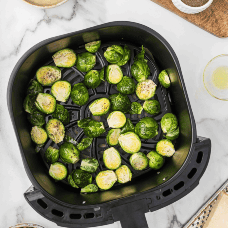 Brussels sprouts cooking in an air fryer basket until crispy and golden brown.