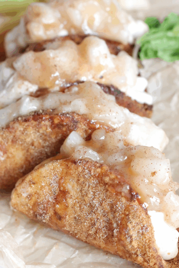 Crispy dessert tacos filled with apple pie filling and creamy cheesecake, served warm.