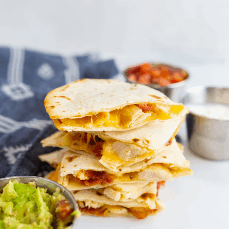 Golden air fryer chicken quesadilla cut into wedges with melted cheese and grilled chicken inside.