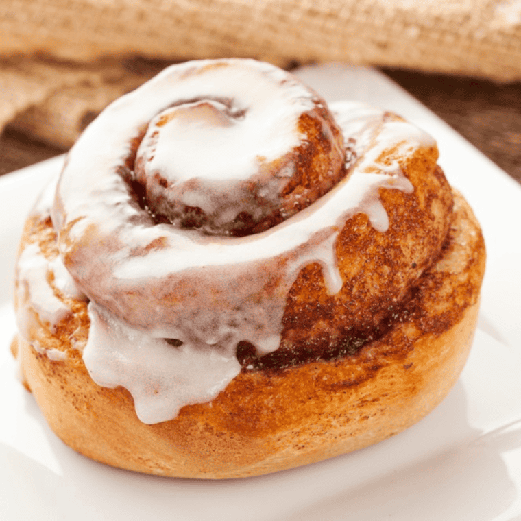 Golden, crispy cinnamon rolls cooked in the air fryer, drizzled with icing and ready to enjoy.