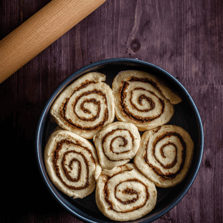 Frozen cinnamon rolls placed in an air fryer basket with space between them for even cooking.
