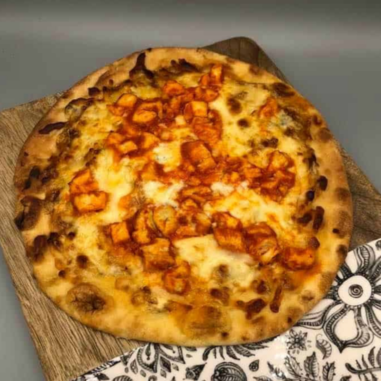 Cooking buffalo chicken naan pizza in air fryer until cheese melts and edges are golden, then topping with ranch and green onions
