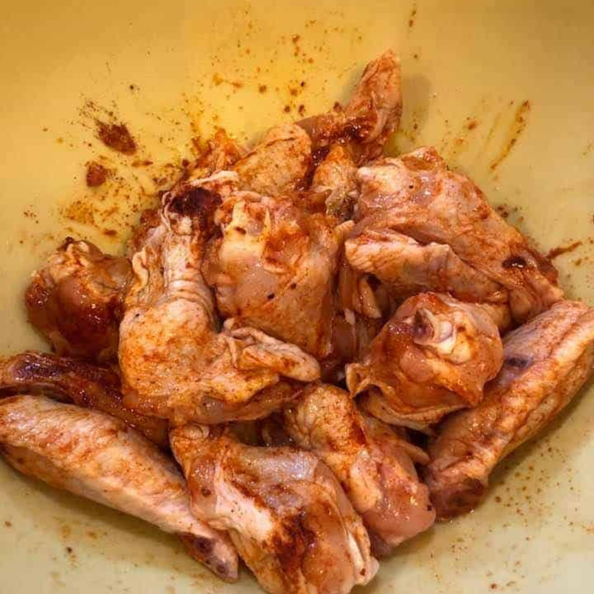 Tossing chicken wings to coat them evenly with seasoning