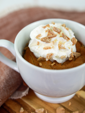 Air fryer peanut butter mug cake in a white mug topped with whipped cream and peanut butter chips