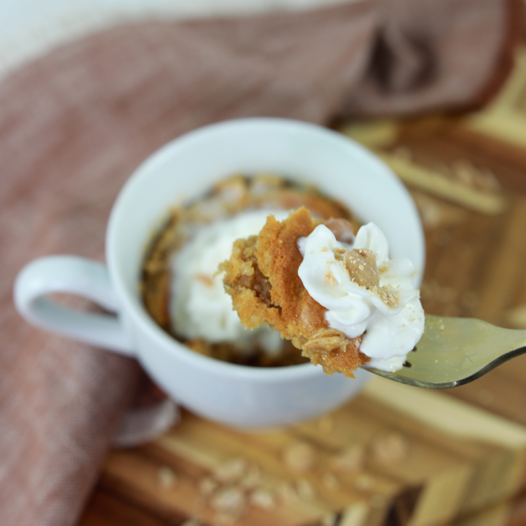 Warm peanut butter mug cake baked in the air fryer, spoon lifting a bite from the mug