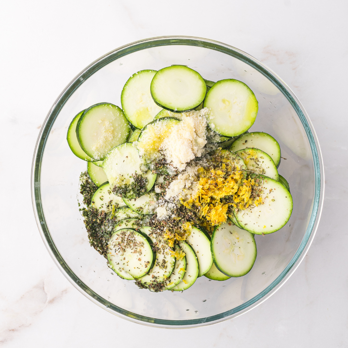 Sprinkling garlic and herbs over the zucchini slices before sealing the foil packet.