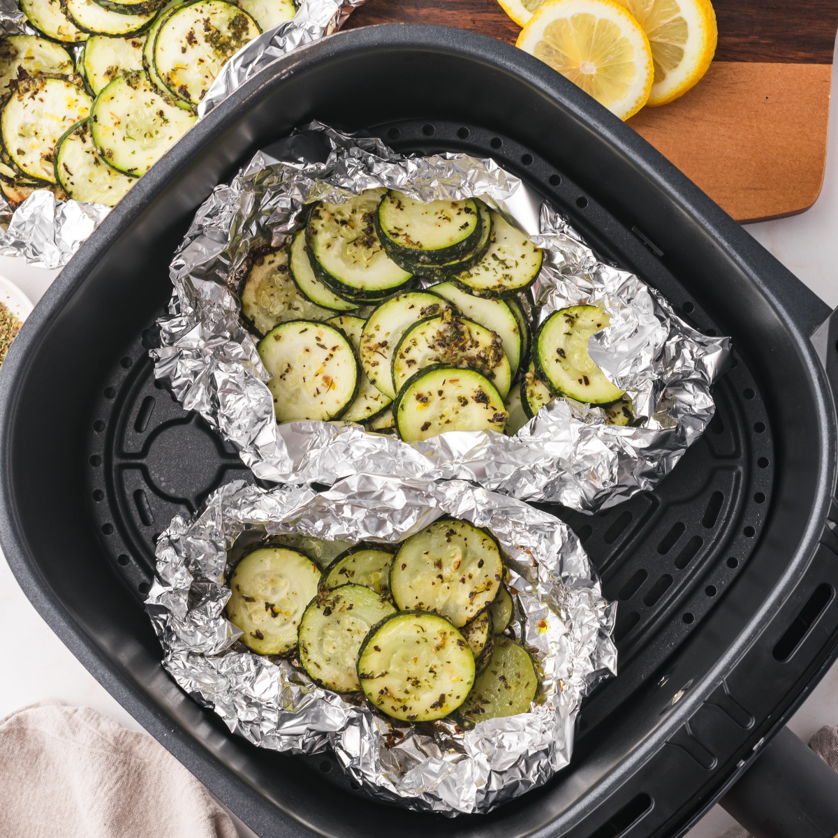 Opening a zucchini foil packet to reveal tender, seasoned vegetables.