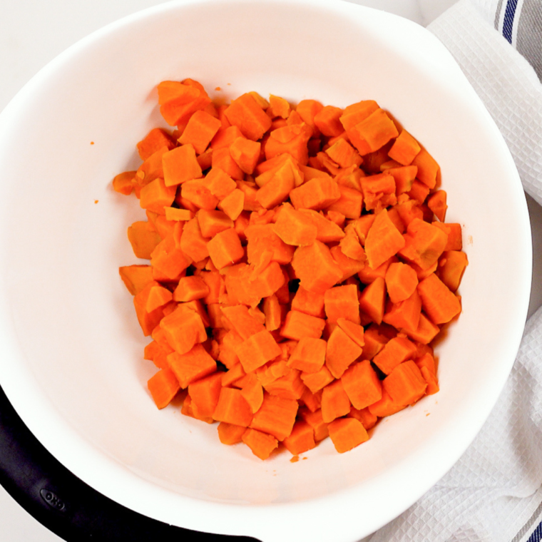 Boiling sweet potatoes in a saucepan until fork-tender.