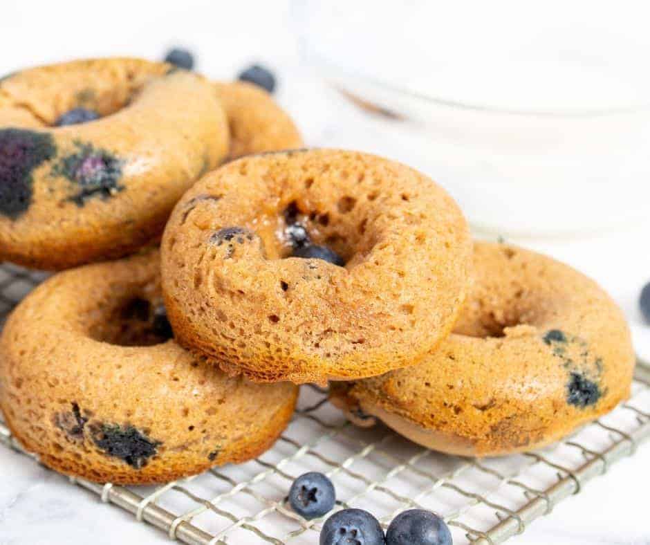 Air-fried blueberry donuts cooling on a wire rack, showing their golden exterior and inviting, round shape.