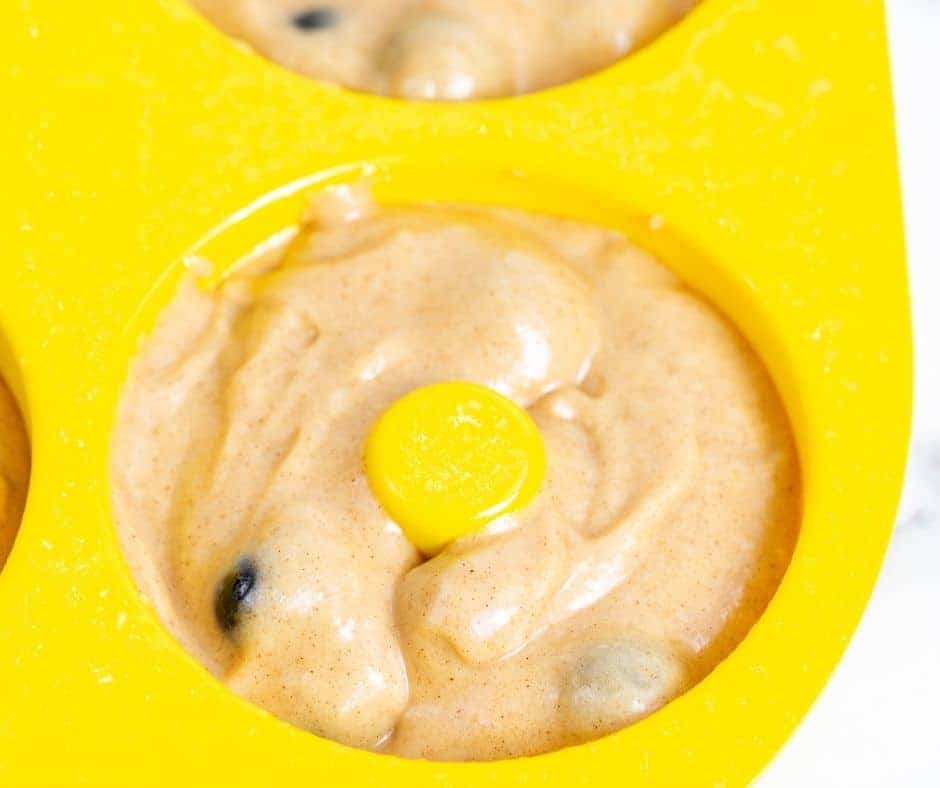 Blueberry donut batter being spooned into silicone donut molds.
