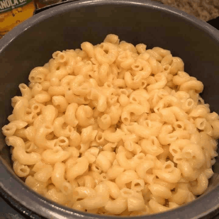 Instant Pot mac and cheese with cheese powder and milk being stirred into creamy pasta