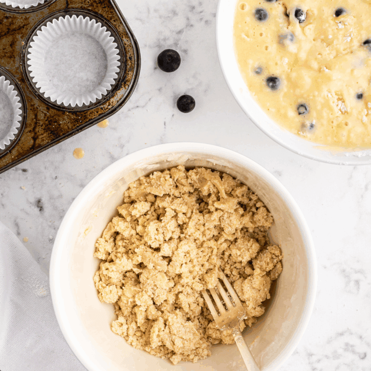 Sprinkling crumb topping over each muffin before air frying