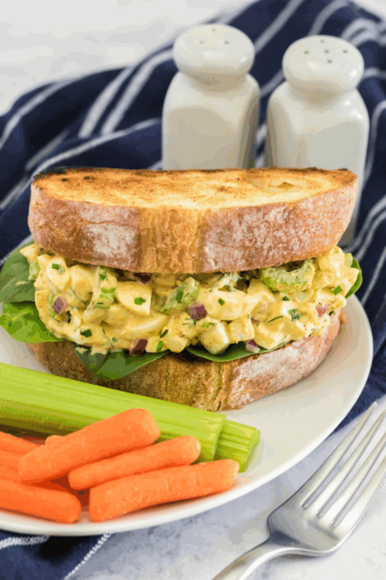 Creamy air fryer egg salad served on toasted bread with lettuce and herbs, ready for a delicious sandwich or snack.