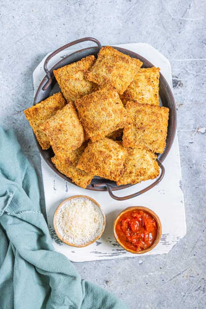 "Golden and crispy Air Fryer Olive Garden Toasted Ravioli served with marinara dipping sauce on a white plate, perfect for an appetizer or snack."