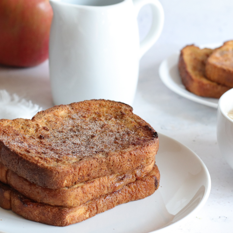 Overhead view of air fryer pumpkin French toast on a plate with sautéed apple slices and maple syrup