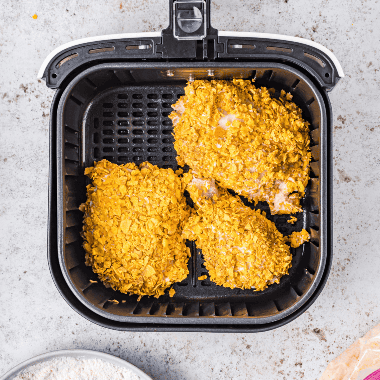 Breaded Captain Crunch Chicken tenders cooking in an air fryer basket