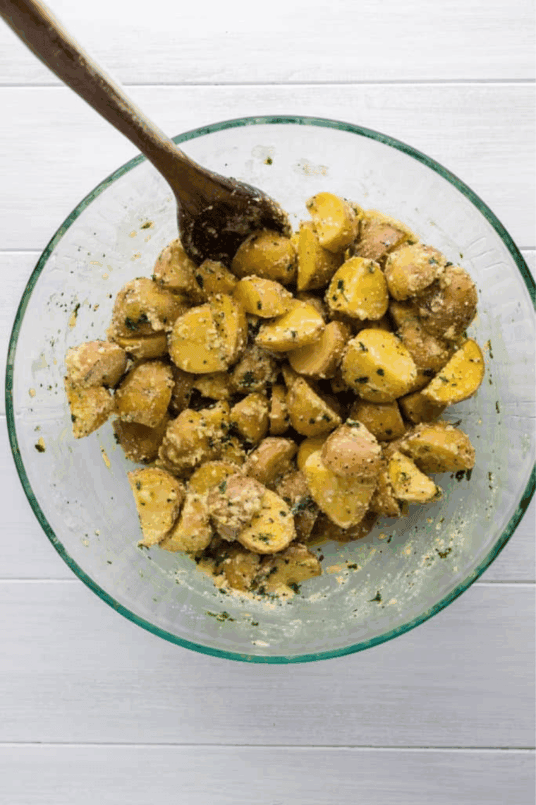 Tossing potatoes, onion, and bell pepper with oil and seasonings in a bowl