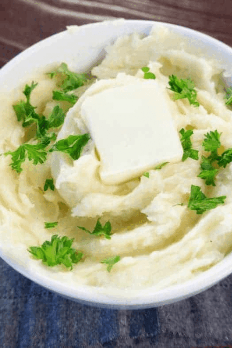 Creamy, golden truffle mashed potatoes garnished with fresh herbs, served alongside a meat entree