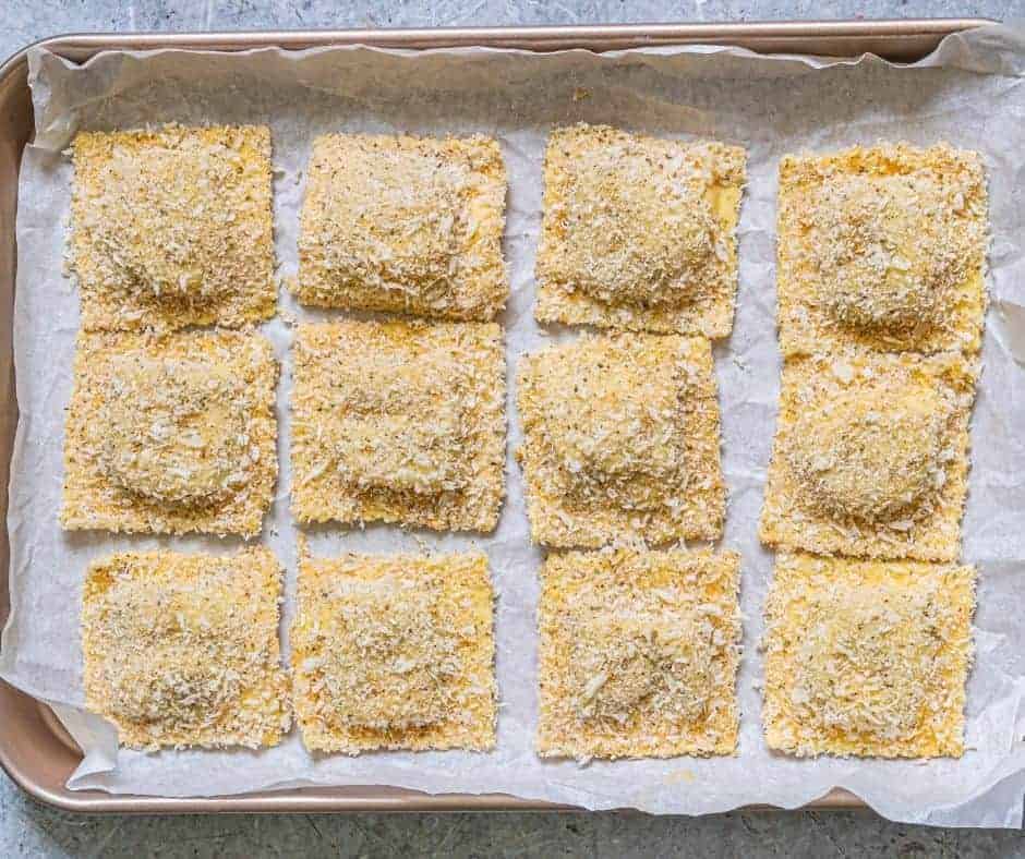 Breaded ravioli on the baking sheet, getting ready for air frying.