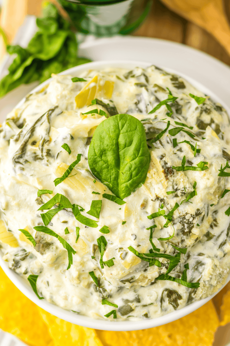 Creamy Instant Pot copycat Olive Garden spinach artichoke dip in a white bowl, served with tortilla chips.