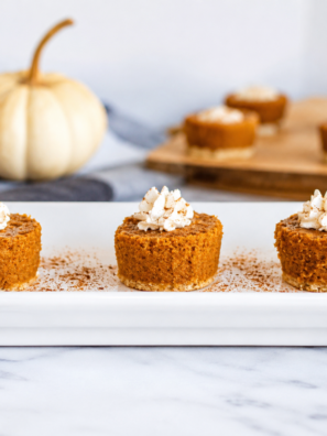 Pumpkin pie bites topped with whipped cream arranged on a slate serving board