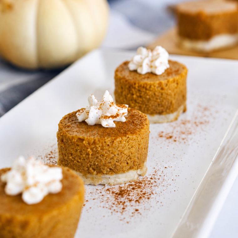 Plate of pumpkin pie bites topped with whipped cream and a dusting of cinnamo