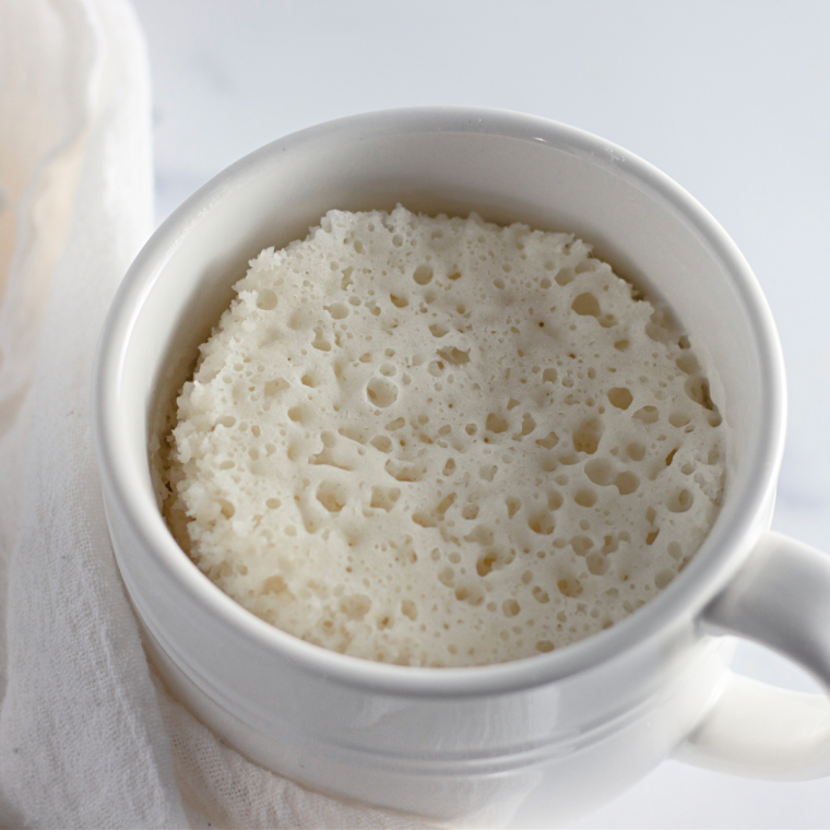 Toothpick inserted into a baked vanilla mug cake coming out clean to test doneness